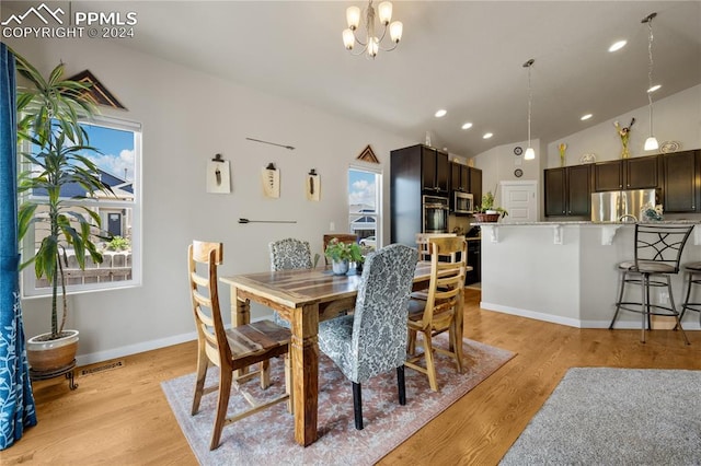 dining space featuring vaulted ceiling, an inviting chandelier, and light wood-type flooring