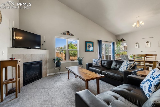 living room with an inviting chandelier, carpet, a tile fireplace, and vaulted ceiling