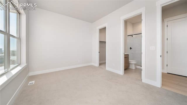 unfurnished bedroom featuring ensuite bathroom and light colored carpet