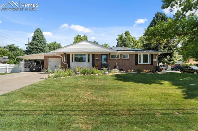 single story home featuring a garage, solar panels, a carport, and a front yard