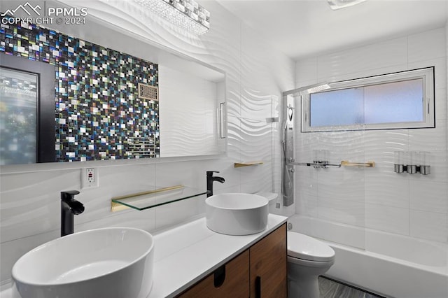 full bathroom with tile walls, toilet, vanity, and tiled shower / bath