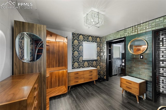 interior space featuring a notable chandelier, dark hardwood / wood-style floors, and tile walls