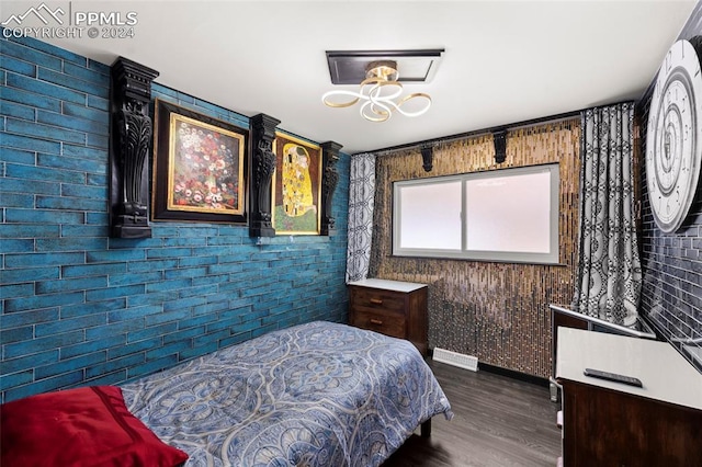 bedroom featuring dark wood-type flooring and brick wall