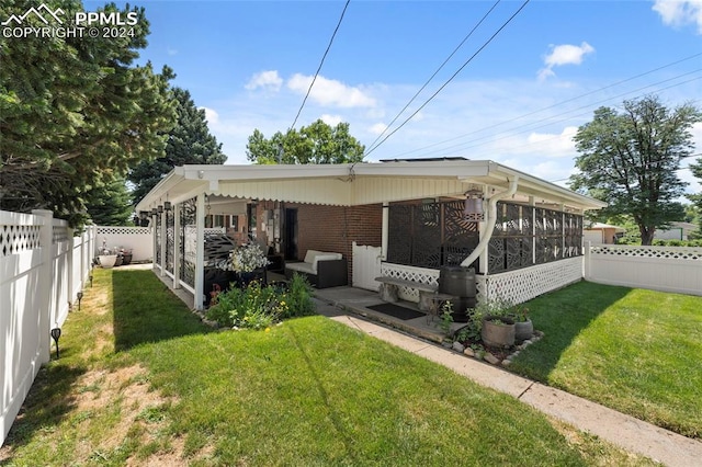 rear view of property with a yard and a sunroom