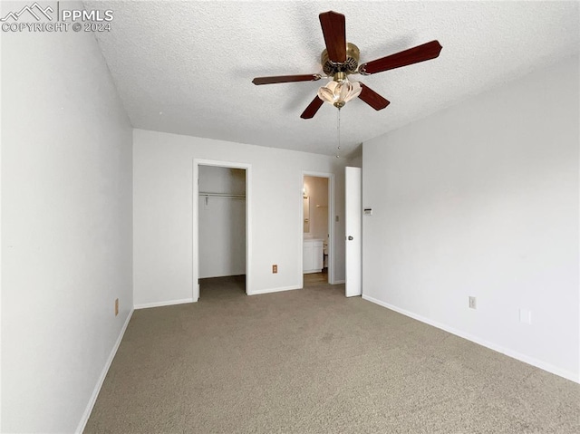 unfurnished bedroom with ensuite bathroom, carpet, a textured ceiling, and ceiling fan