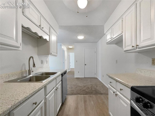 kitchen with stainless steel appliances, sink, white cabinets, and light hardwood / wood-style floors