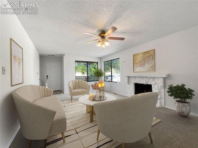 living room with carpet floors, a high end fireplace, and a textured ceiling