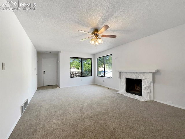 unfurnished living room with a textured ceiling, carpet, a high end fireplace, and ceiling fan