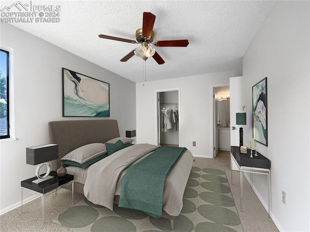 bedroom with ensuite bathroom, a walk in closet, a textured ceiling, and ceiling fan