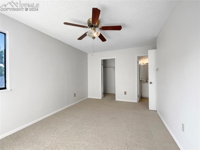 unfurnished bedroom with ceiling fan, light colored carpet, and a textured ceiling