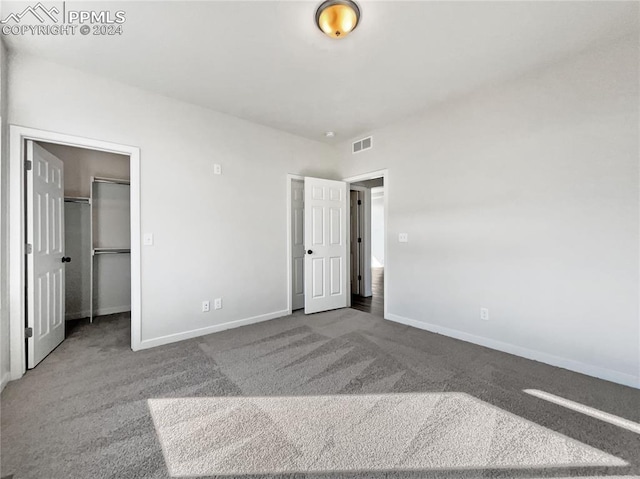 unfurnished bedroom with a closet, a walk in closet, and carpet floors