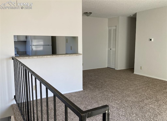 kitchen featuring carpet, stainless steel fridge, and a textured ceiling