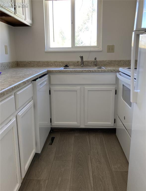 kitchen with dark wood-type flooring, sink, white appliances, and white cabinetry