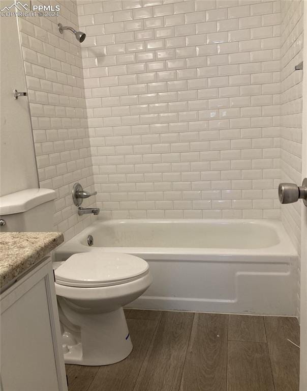 full bathroom with tiled shower / bath, vanity, hardwood / wood-style floors, and toilet