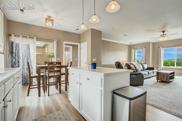 kitchen with white cabinetry, hanging light fixtures, a center island, ceiling fan, and light wood-type flooring