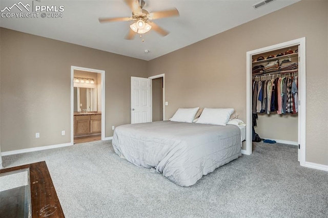 bedroom with a walk in closet, ensuite bathroom, light colored carpet, and a closet