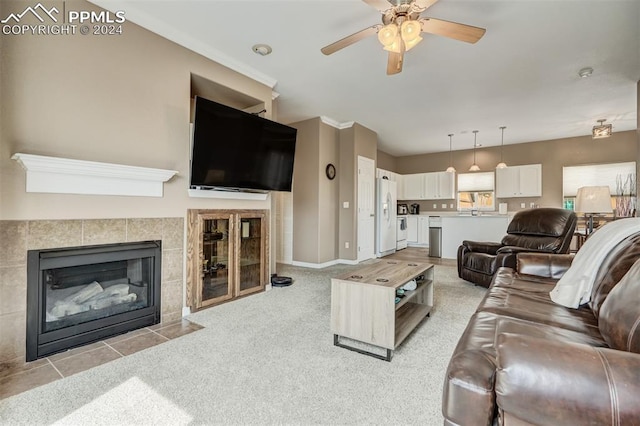 living room featuring ceiling fan, light colored carpet, and a tiled fireplace