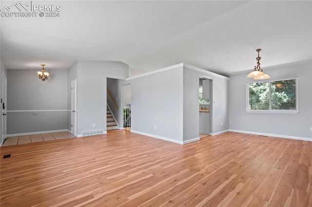 empty room featuring an inviting chandelier and light hardwood / wood-style floors