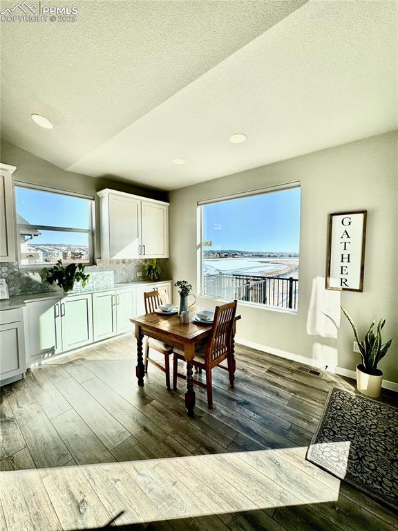 dining area with dark hardwood / wood-style flooring, vaulted ceiling, and a textured ceiling