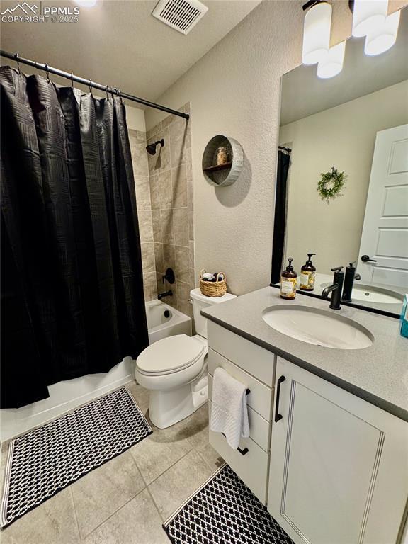 full bathroom featuring shower / bathtub combination with curtain, vanity, tile patterned flooring, and toilet