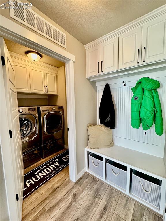 mudroom featuring washing machine and dryer, a textured ceiling, and light hardwood / wood-style flooring