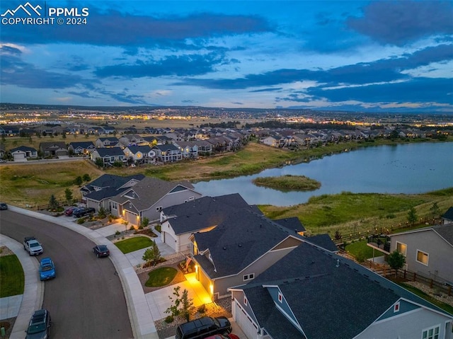 aerial view at dusk featuring a water view