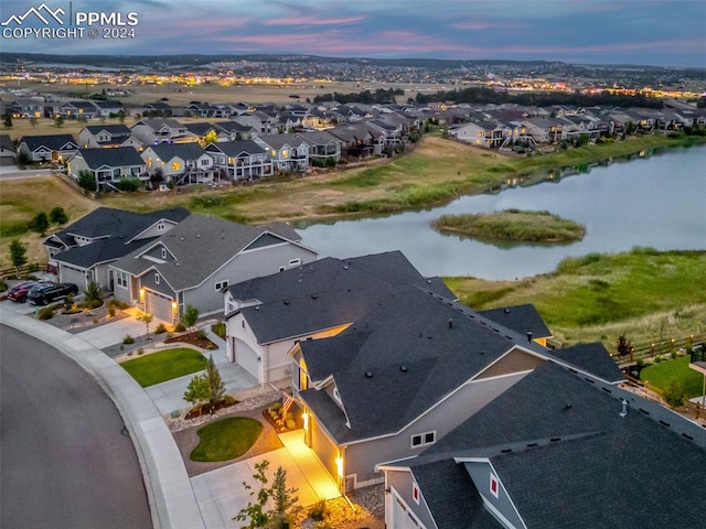 aerial view at dusk featuring a water view