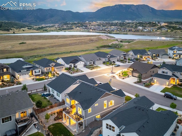 aerial view at dusk featuring a water and mountain view