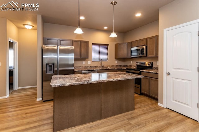 kitchen featuring a center island, pendant lighting, light wood-type flooring, and appliances with stainless steel finishes