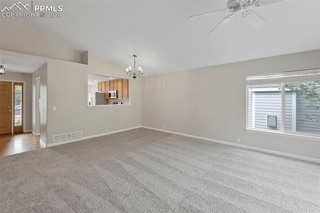 interior space featuring baseboards, visible vents, vaulted ceiling, carpet floors, and ceiling fan with notable chandelier