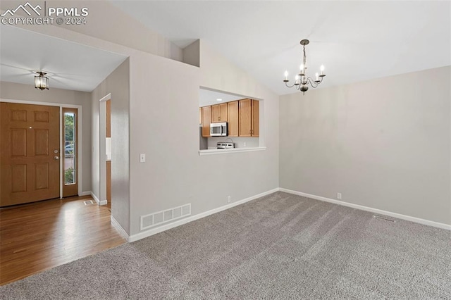 carpeted entrance foyer with vaulted ceiling and a notable chandelier