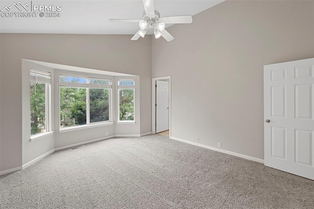 spare room with high vaulted ceiling, carpet flooring, a ceiling fan, visible vents, and baseboards