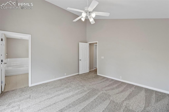 unfurnished bedroom featuring baseboards, ensuite bath, tile patterned floors, carpet floors, and high vaulted ceiling