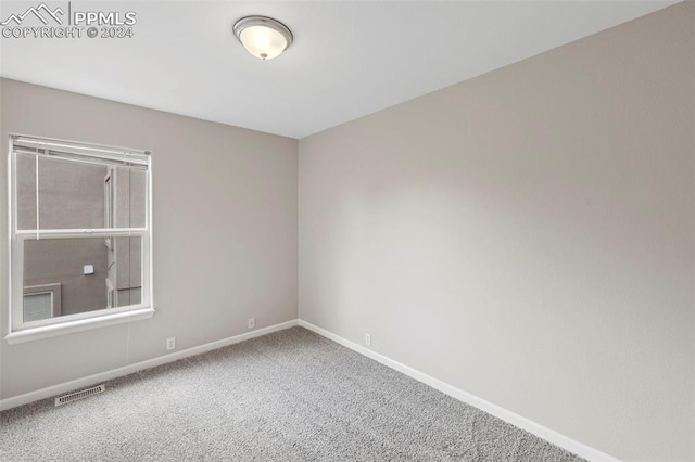 unfurnished room with carpet, visible vents, and baseboards