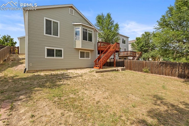 rear view of property with a fenced backyard, stairway, a lawn, and a wooden deck