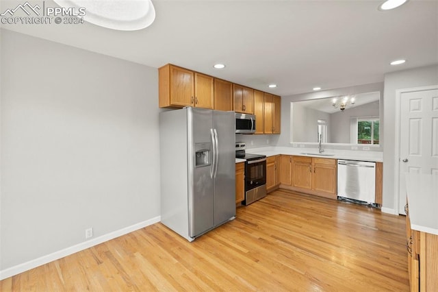 kitchen with light wood finished floors, recessed lighting, light countertops, appliances with stainless steel finishes, and a sink