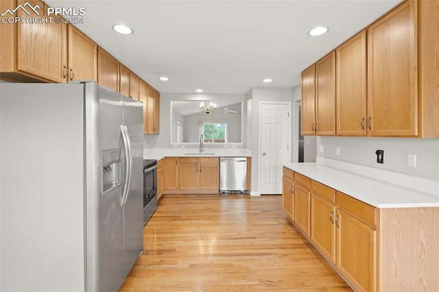 kitchen with appliances with stainless steel finishes, light countertops, light wood-type flooring, a sink, and recessed lighting