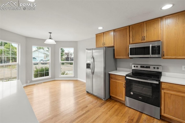 kitchen featuring light countertops, appliances with stainless steel finishes, brown cabinetry, and light wood-type flooring