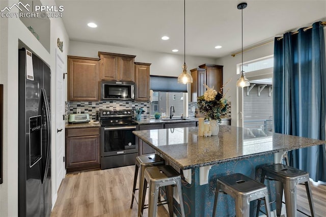 kitchen with a breakfast bar area, a center island, dark stone countertops, pendant lighting, and stainless steel appliances