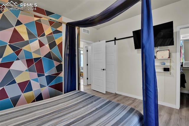 unfurnished bedroom featuring wood-type flooring and a barn door