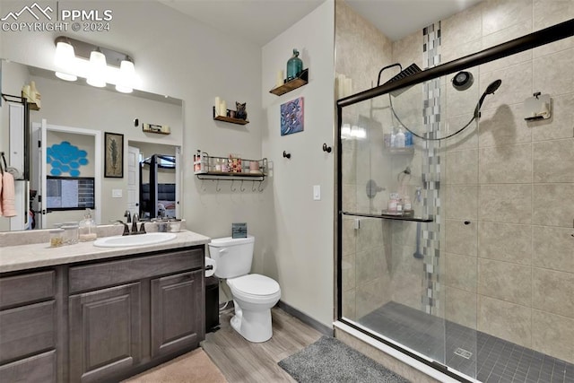 bathroom with walk in shower, vanity, toilet, and hardwood / wood-style floors