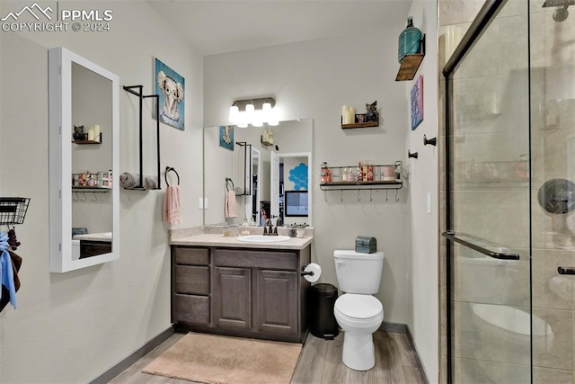 bathroom with vanity, hardwood / wood-style flooring, a shower with door, and toilet