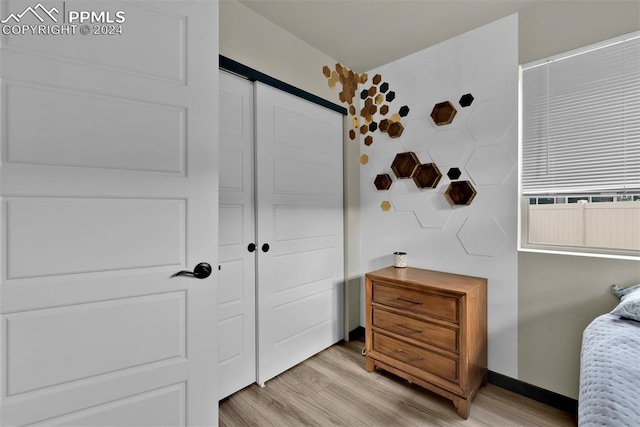 bedroom with light hardwood / wood-style floors and a closet