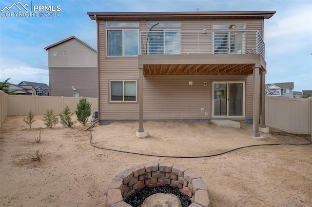 back of property with a balcony, an outdoor fire pit, and a patio