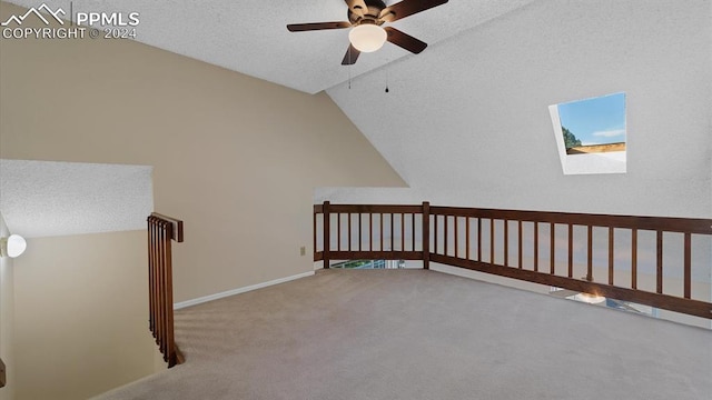 additional living space featuring carpet floors, a textured ceiling, ceiling fan, and vaulted ceiling with skylight