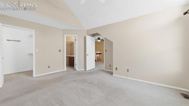 unfurnished bedroom with a closet, a spacious closet, ceiling fan, carpet flooring, and lofted ceiling