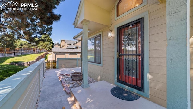 doorway to property with covered porch and a lawn