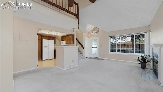 unfurnished living room featuring high vaulted ceiling and light colored carpet