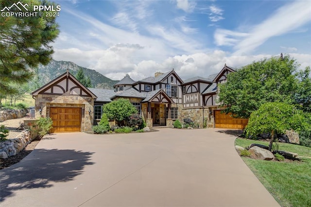 english style home with a garage and a mountain view