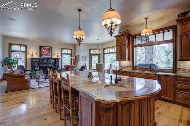4950 Longwood Pt, Colorado Springs, CO 80906 - kitchen with stone countertops, light wood-style flooring, a premium fireplace, a sink, and backsplash